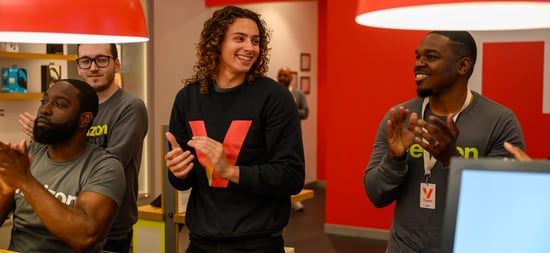 a group of men standing in a room clapping.